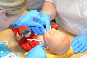 Two participants in a simulation suite working on a high fidelity mannequin baby