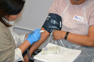 Two participants in a simulation with one checking the blood pressure of the other.