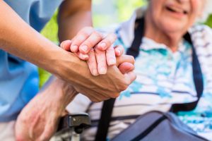 Frail older person holding hands with someone younger